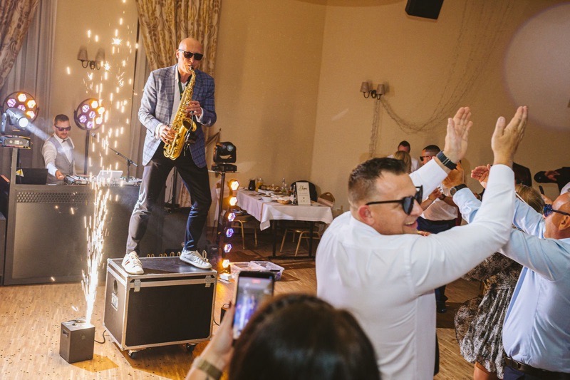 Saksofon na żywo w trakcie seta DJ-a: fontanny iskier, DJ przy konsolecie i pełny parkiet